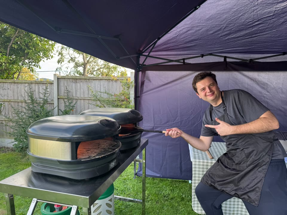 Pizza maker tending an outdoor oven