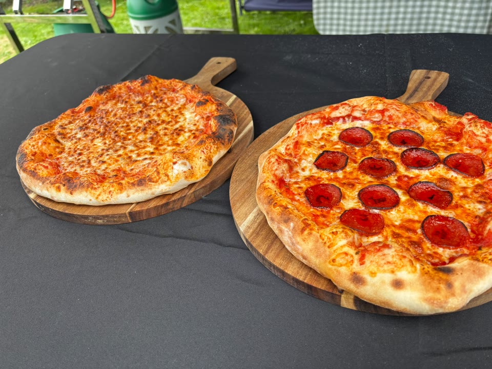 Freshly cooked cheese and pepperoni pizzas on wooden serving boards